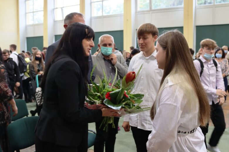 Uczniowie prowadzący uroczystość składają kwiaty na ręce pani dyrektor z okazji Dnia Edukacji Narodowej.