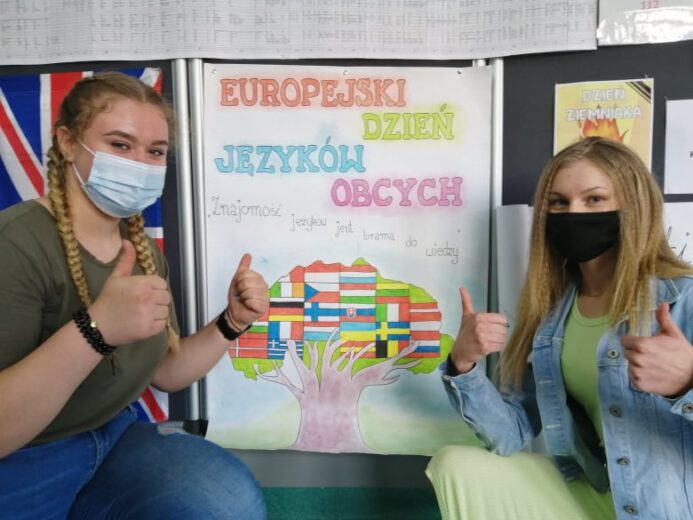 Uczennice promujące Europejski Dzień Języków Obcych. W tle jednen z plakatów wykonany przez uczniów.