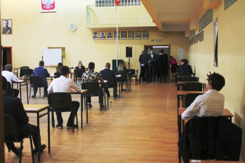 Uczniowie losują miejsca podczas egzaminu na auli.