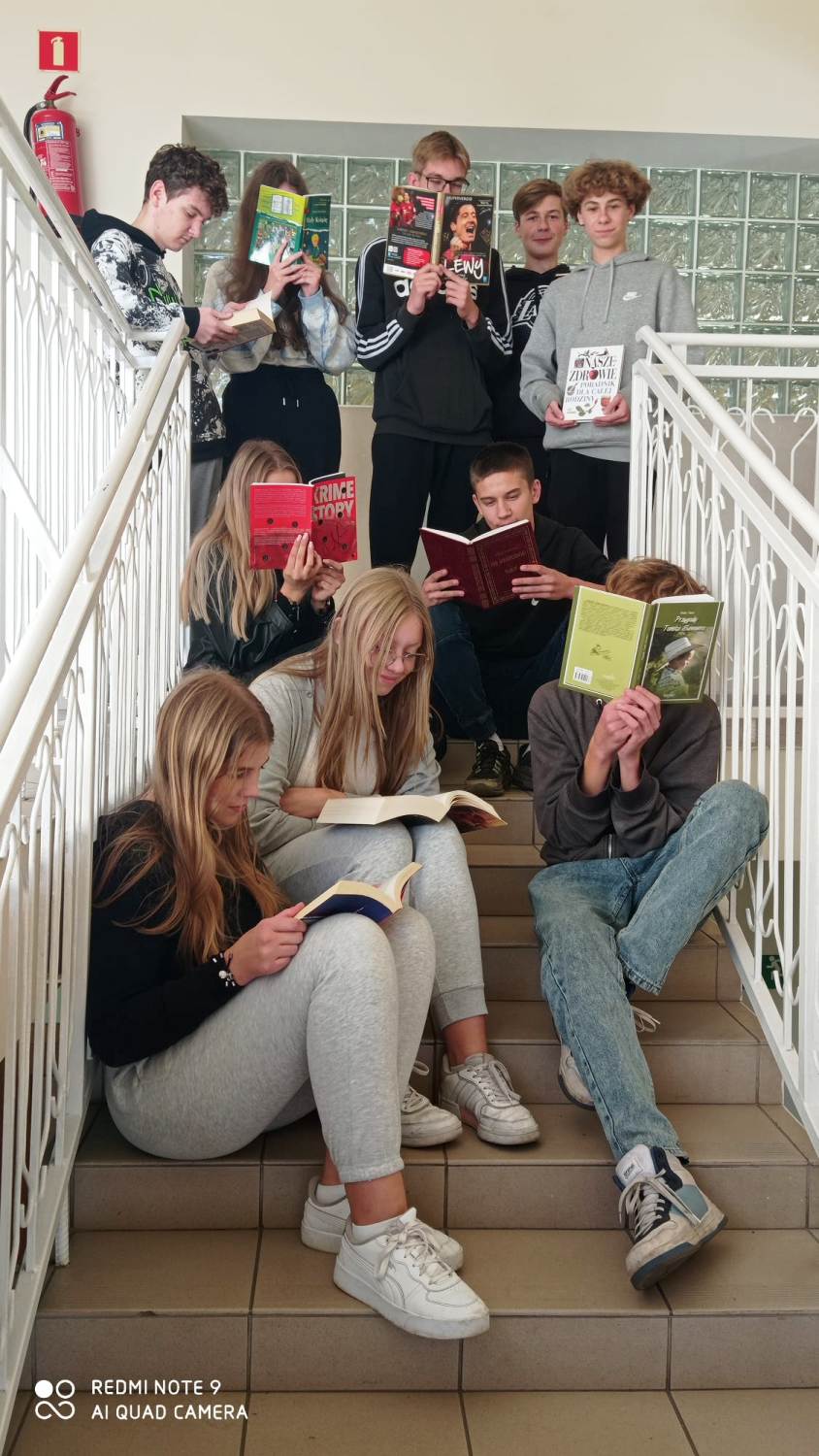 Akcja przerwa na czytanie - uczniowie czytają książki na schodach przy auli szkolnej