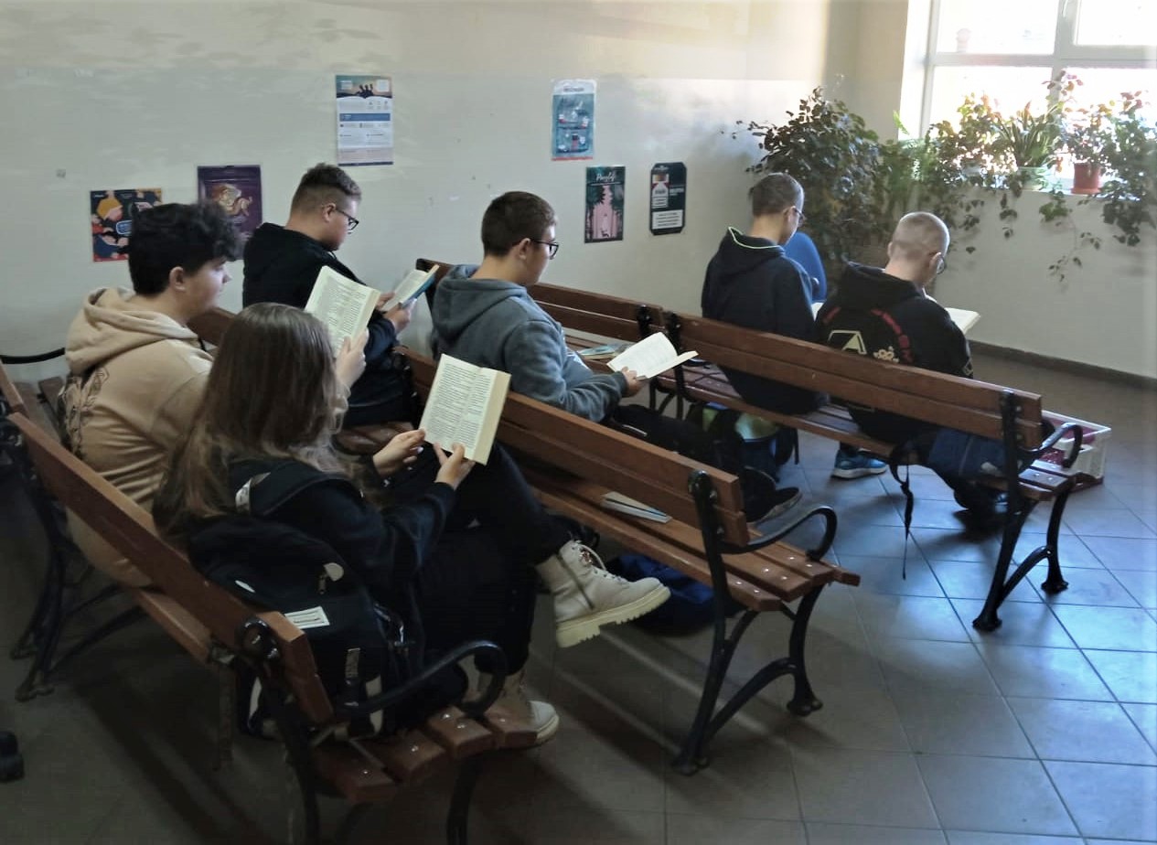 Akcja przerwa na czytanie - uczniowie czytają książki na ławkach koło auli szkolnej