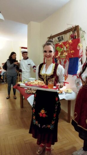 Degustacja regionalnych potraw podczas warsztatów kulinarnych - na zdjęciu hostessa w regionalnym stroju z poczęstunkiem