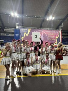 Zdjęcie grupowe zespołu UKS Mażoretki Artis Góra biorącego udział w XXVI Mistrzostwa Polski Mażoretek w Kędzierzynie-Koźlu wraz ze zdobytymi medalami, w tym m. in. Mistrzostwa Polski w kat. scena buława seniorki „Upiór w operze".