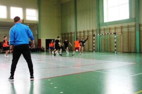 Jedną z atrakcji "Dnia sportu" był turniej piłki nożnej halowej. Zdjęcie jednego z meczów turniejowych. Bramkarz wybija piłkę, ubiegając napastnika próbującego oddać strzał.