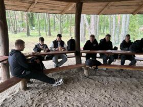 Uczniowie podczas wyjścia na strzelnicę z okazji Dnia Chłopaka jedli kiełbaski z grilla.