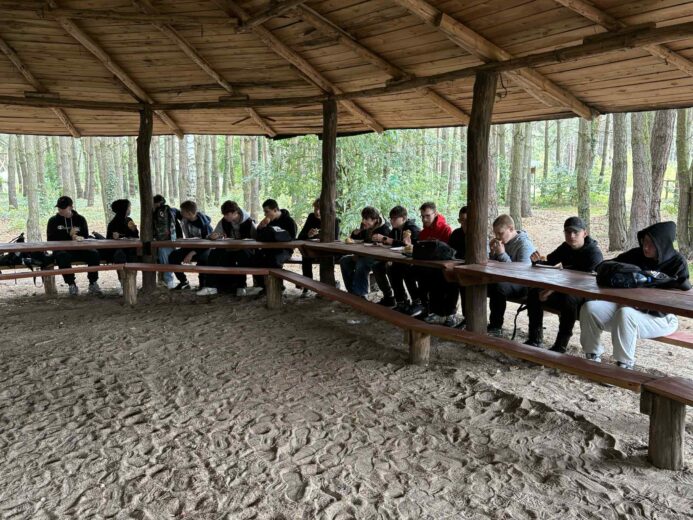 Uczniowie podczas wyjścia na strzelnicę z okazji Dnia Chłopaka jedli kiełbaski z grilla.